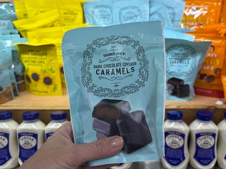 A hand holding a bag of Trader Joe's dark chocolate covered caramels.