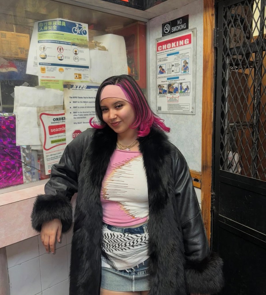 iman abdul in a black coat and pink and white dress looking atthe camera