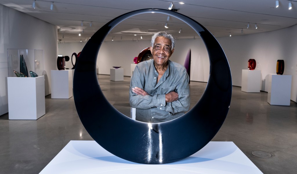 Fred Eversley standing behind his artwork at the Orange County Museum of Art.