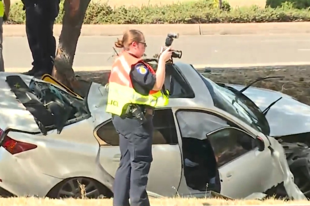 Police officer photographing a damaged car at an accident scene.