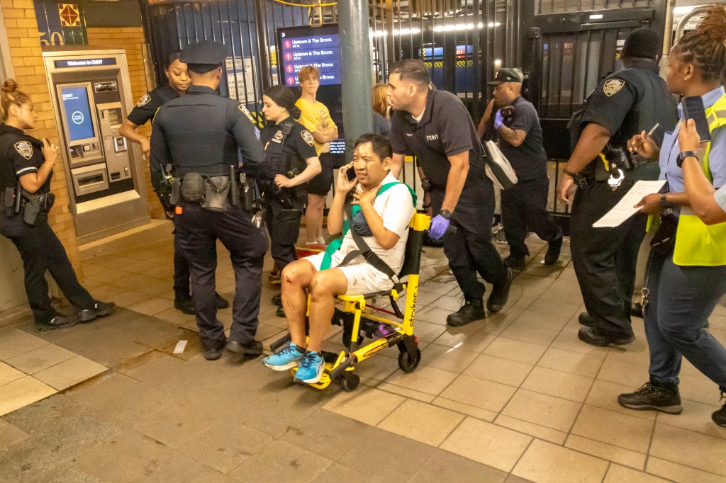 A person injured on a subway platform is being helped into a wheelchair by first responders.