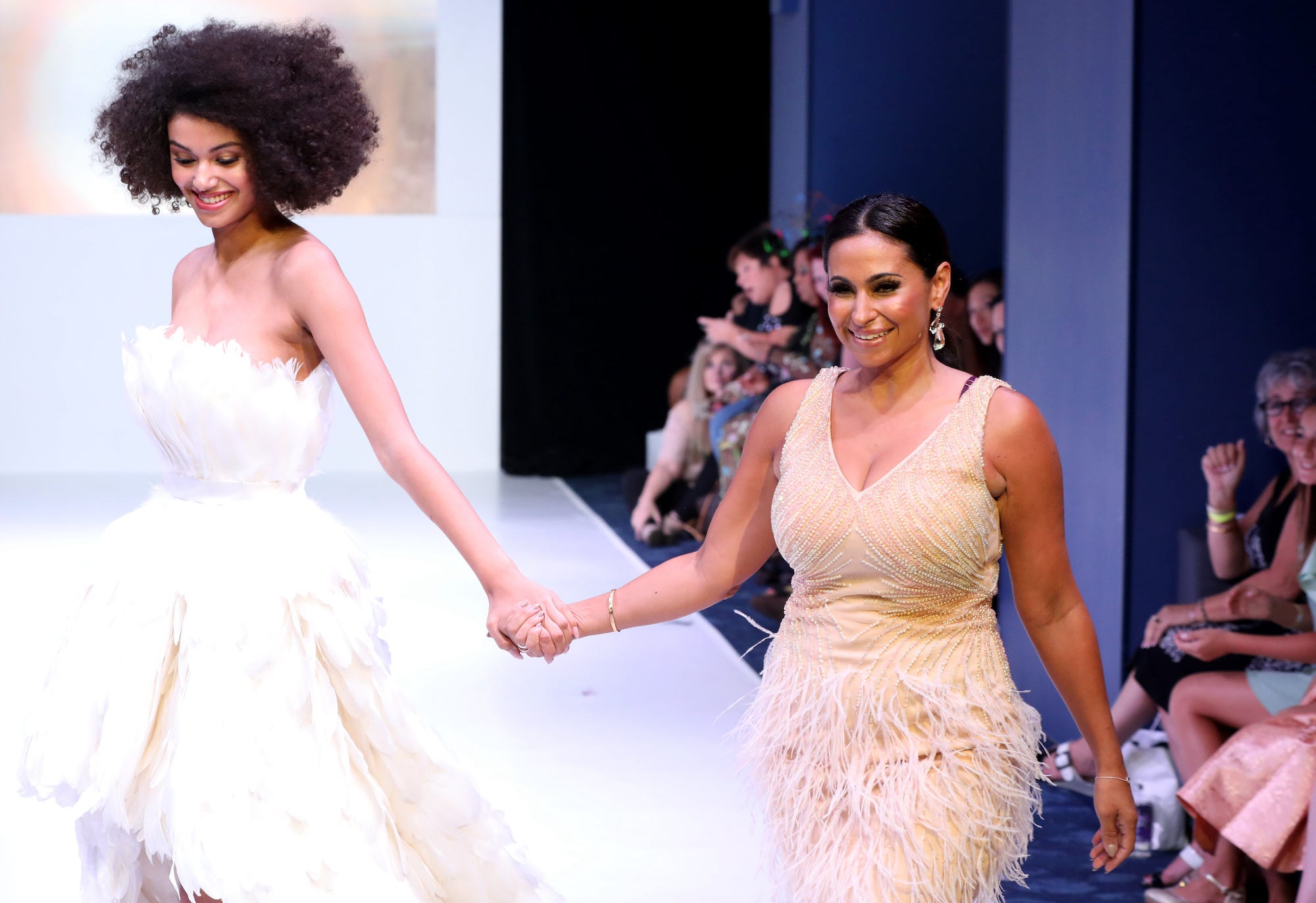 Miss USA organization president Laylah Rose walking hand-in-hand with a model during a fashion show.
