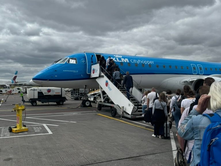 people queuing to board a KLM flight on a runway