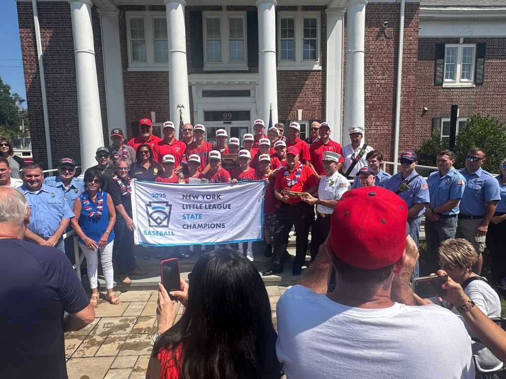 The St. James-Smithtown Little League team hold their state championship banner at Smithtown Town Hall after a parade on Aug. 10, 2025.