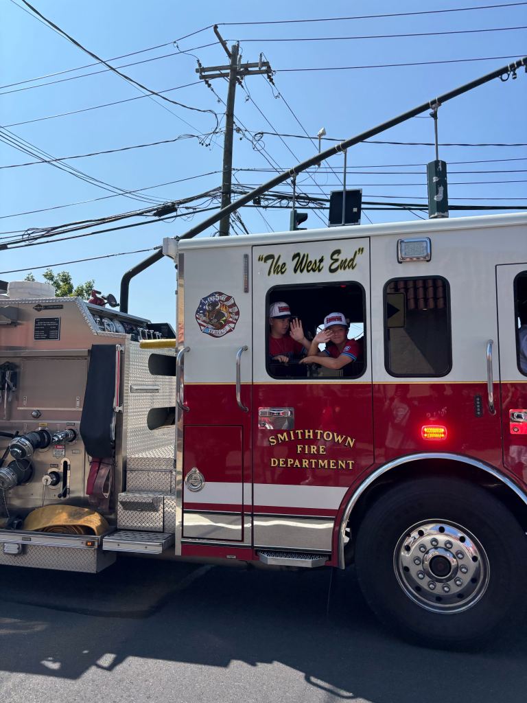 Members of the St. James-Smithtown Little League team ride in fire trucks during a parade honoring the team on Aug. 10, 2025.