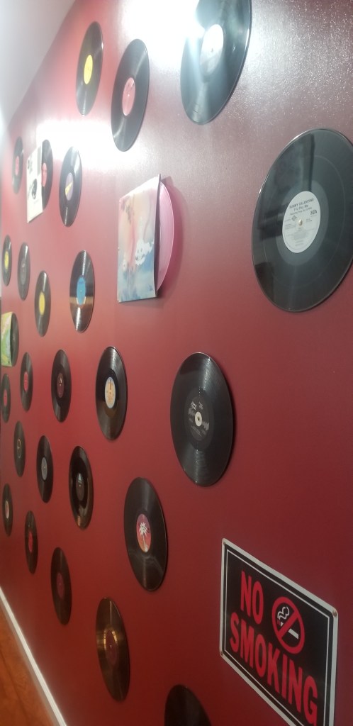 Vinyl records mounted on a red wall; no smoking sign.