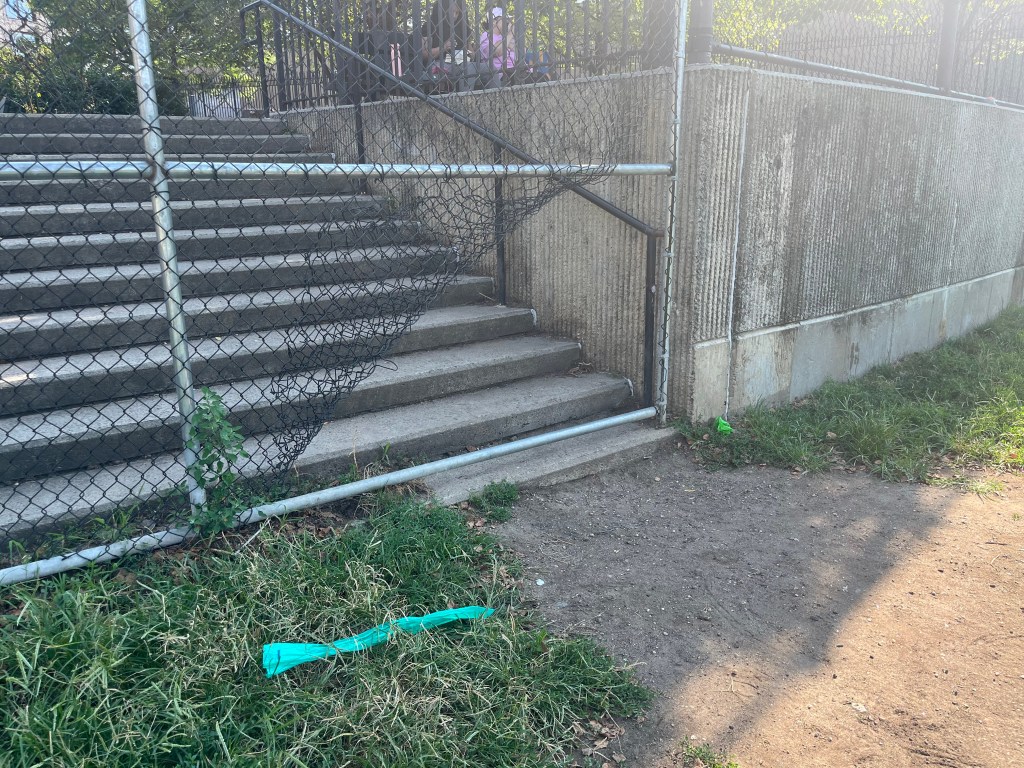 Damaged chain link fence at the bottom of a concrete staircase.