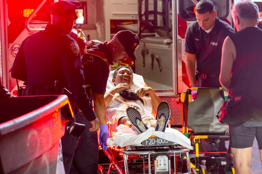 A man is loaded onto a stretcher by NYPD and EMTs.