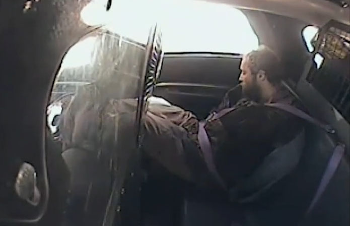 Man restrained in the back of a police car.