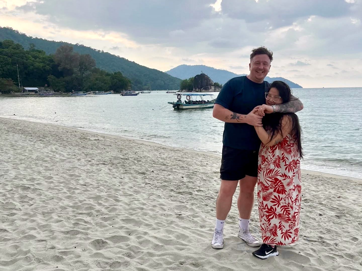A couple posing on a beach.