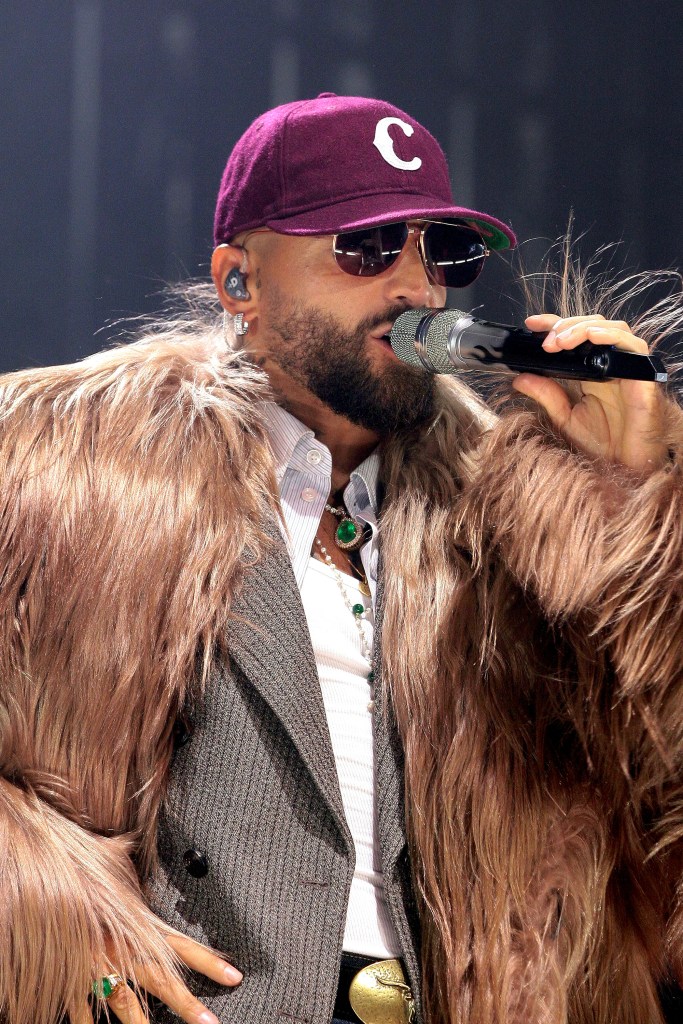 Maluma singing in a fur coat and a baseball hat.