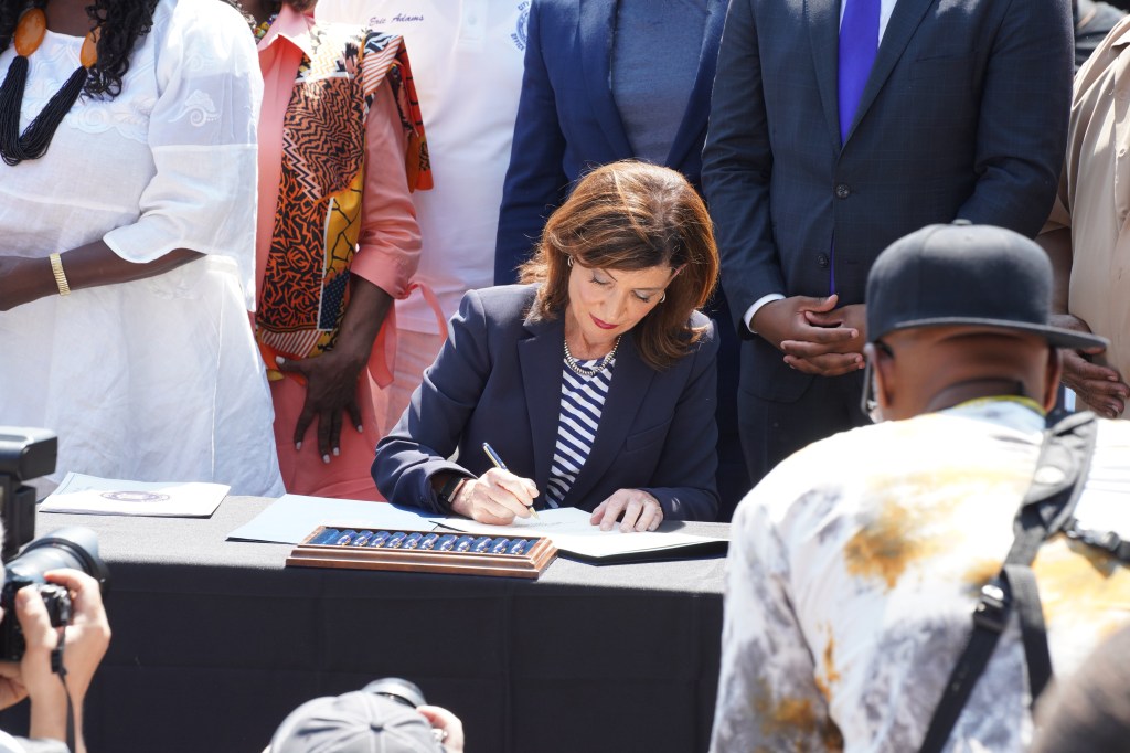 Woman signing a document at a public event.