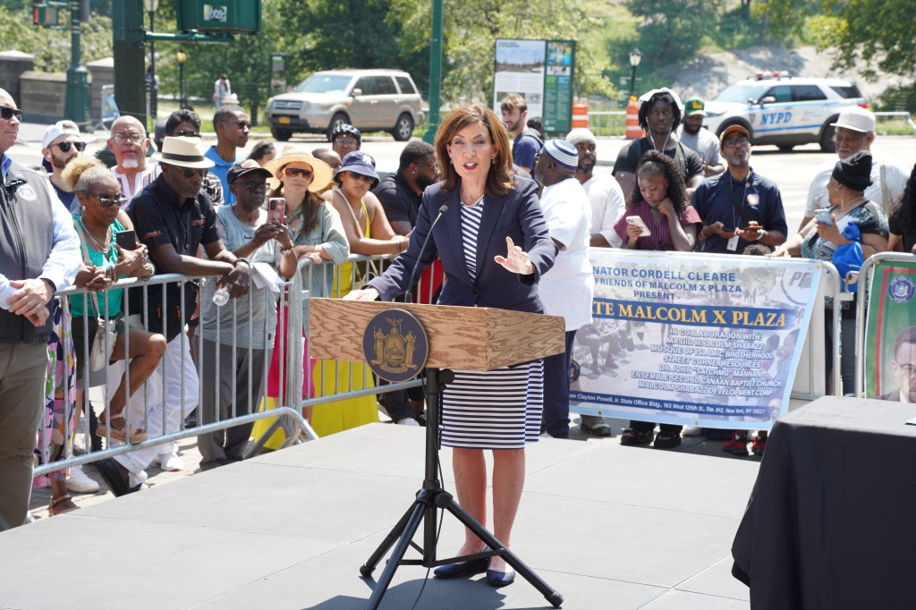 Woman speaking at podium at Malcolm X Plaza event.