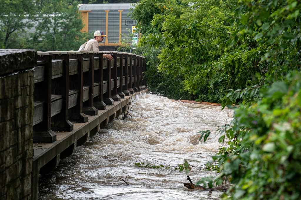 A man watches the Menomonee River flow under a bridge on August 10, 2025 in Wauwatosa, Wisconsin.