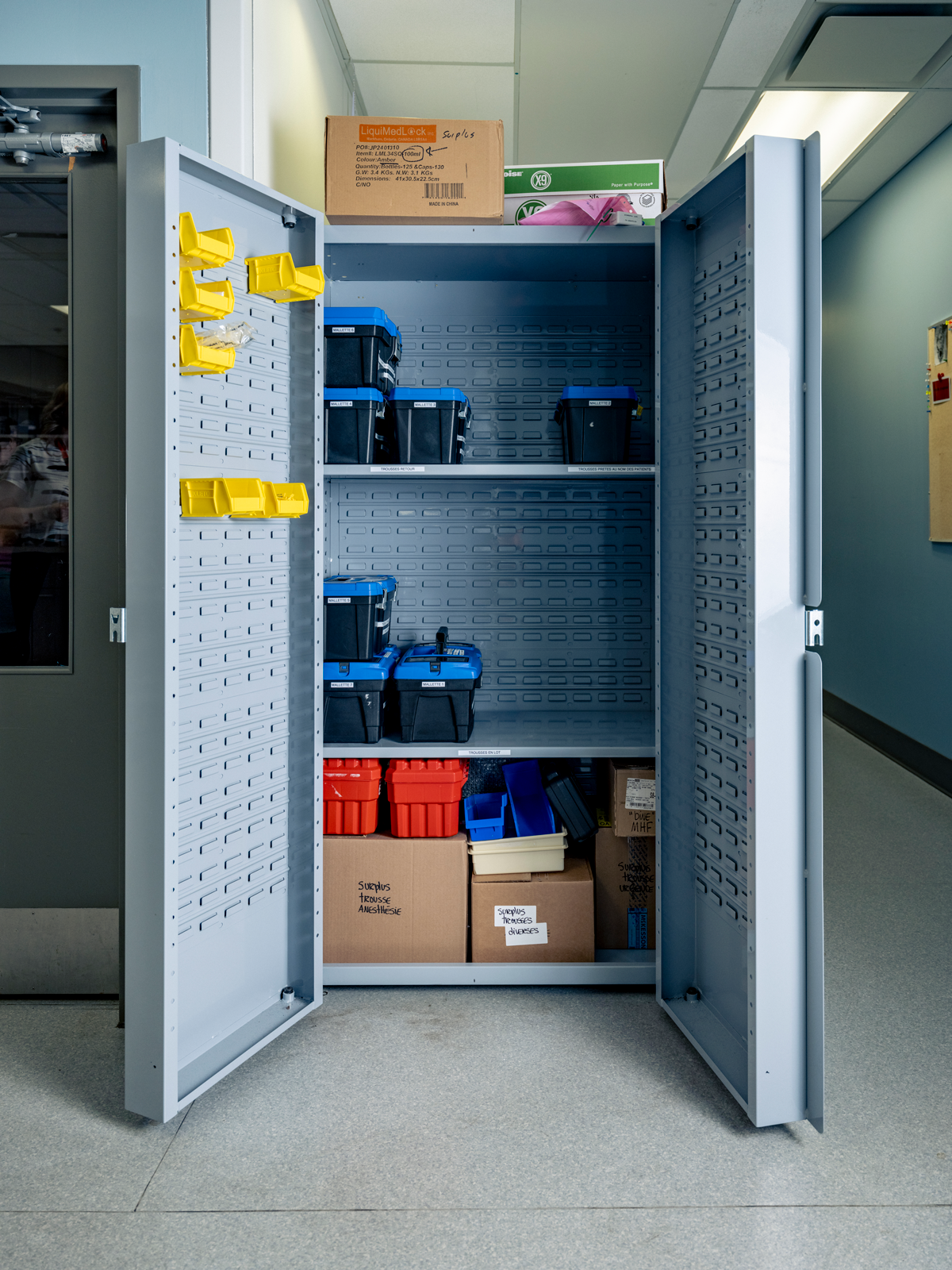 photo of same tall gray medical cabinet open to reveal bins and boxes stored inside