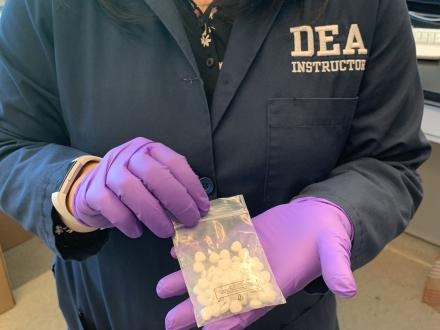 DEA instructor holding a bag of isotonitazene pills.