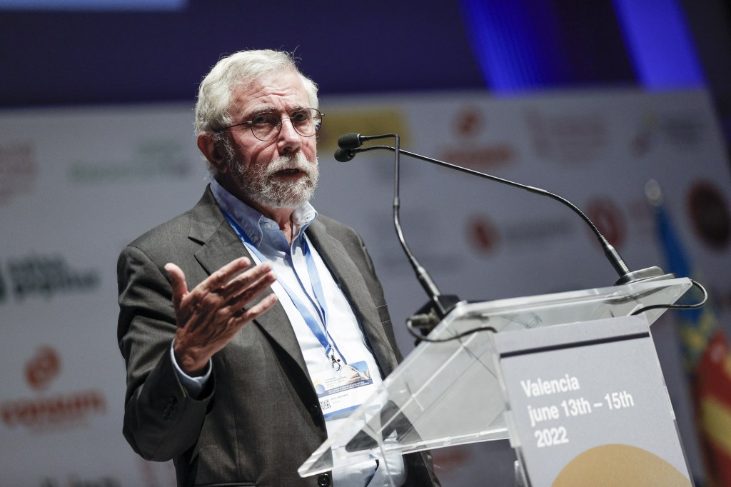 Paul Krugman speaking at a podium.