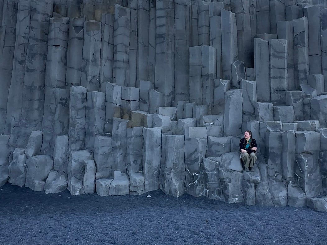 The author sitting for a picture at Reynisfjara Beach in Iceland.