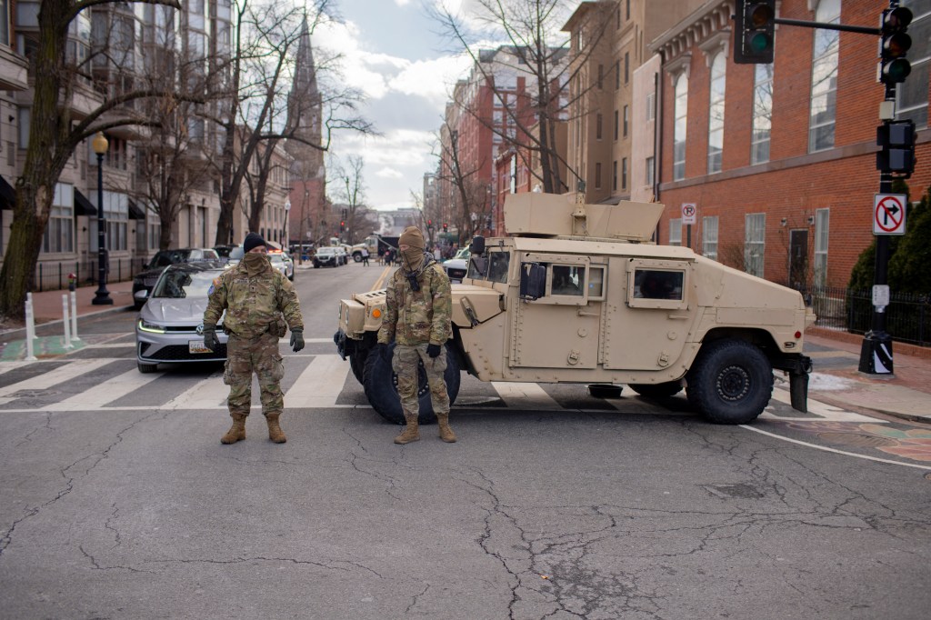 Two National Guard members stand guard near a military vehicle in Washington, D.C.