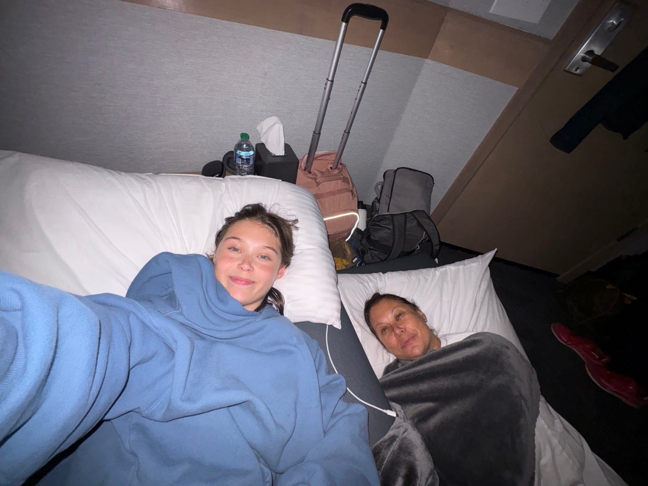 Author Jenny powers and her daughter lying on daybed and trundle bed under blankets with pillows