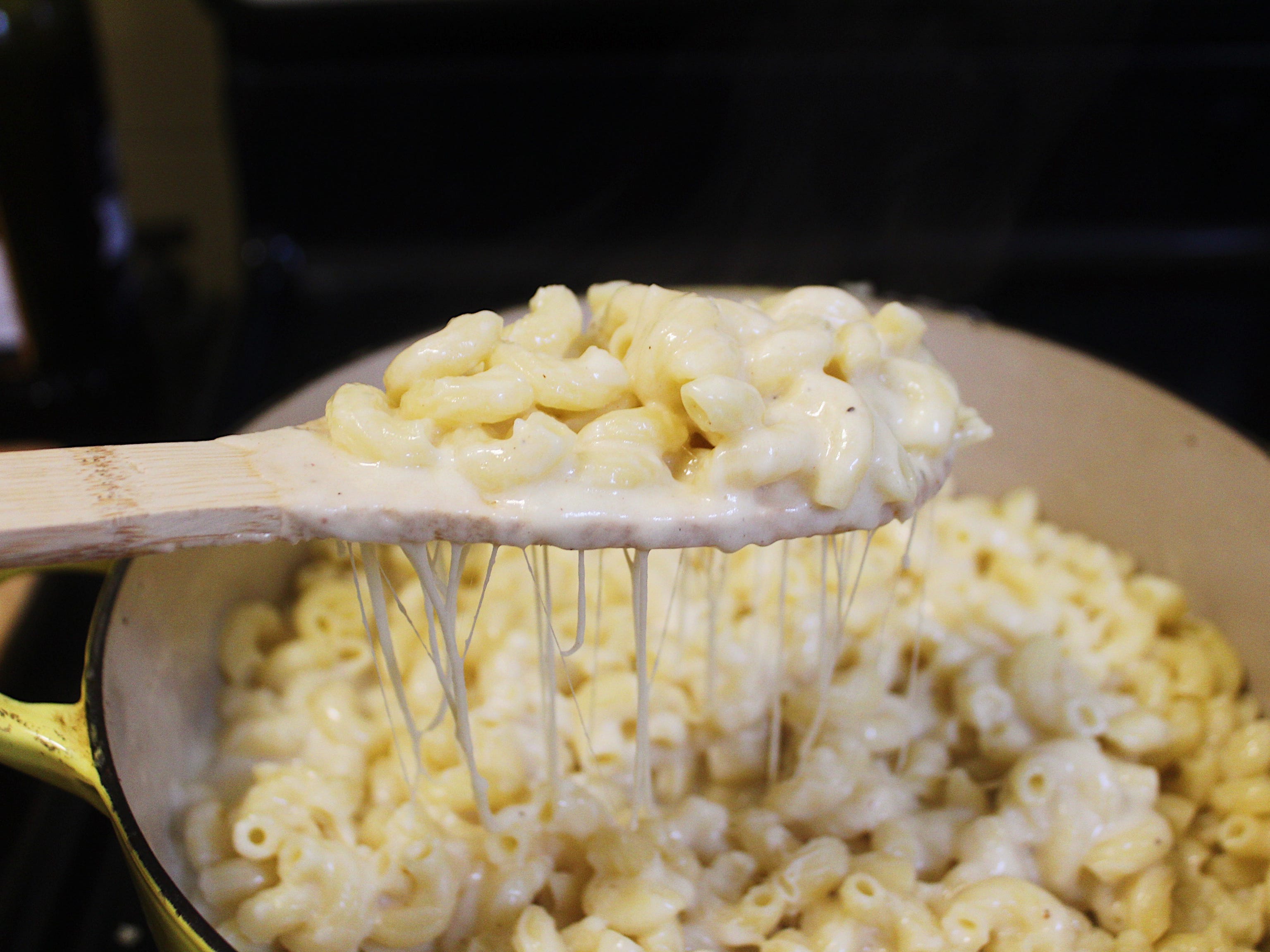 macaroni mixed with cheese sauce and a wooden spoon