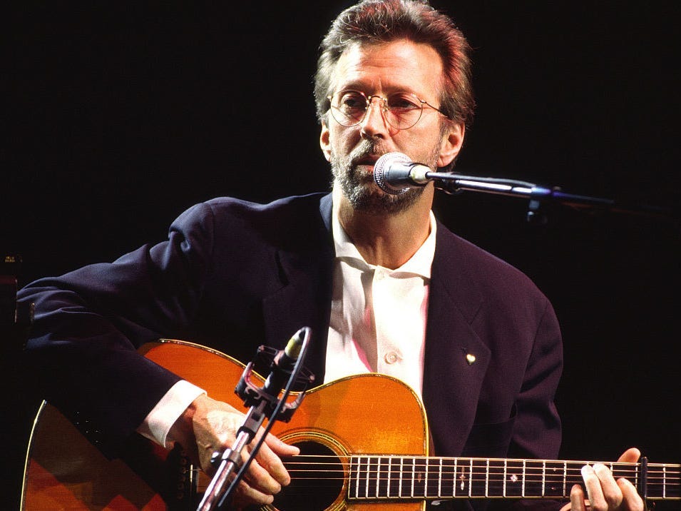Eric Clapton performs on stage playing acoustic guitar at the Royal Albert Hall, London, 1998.