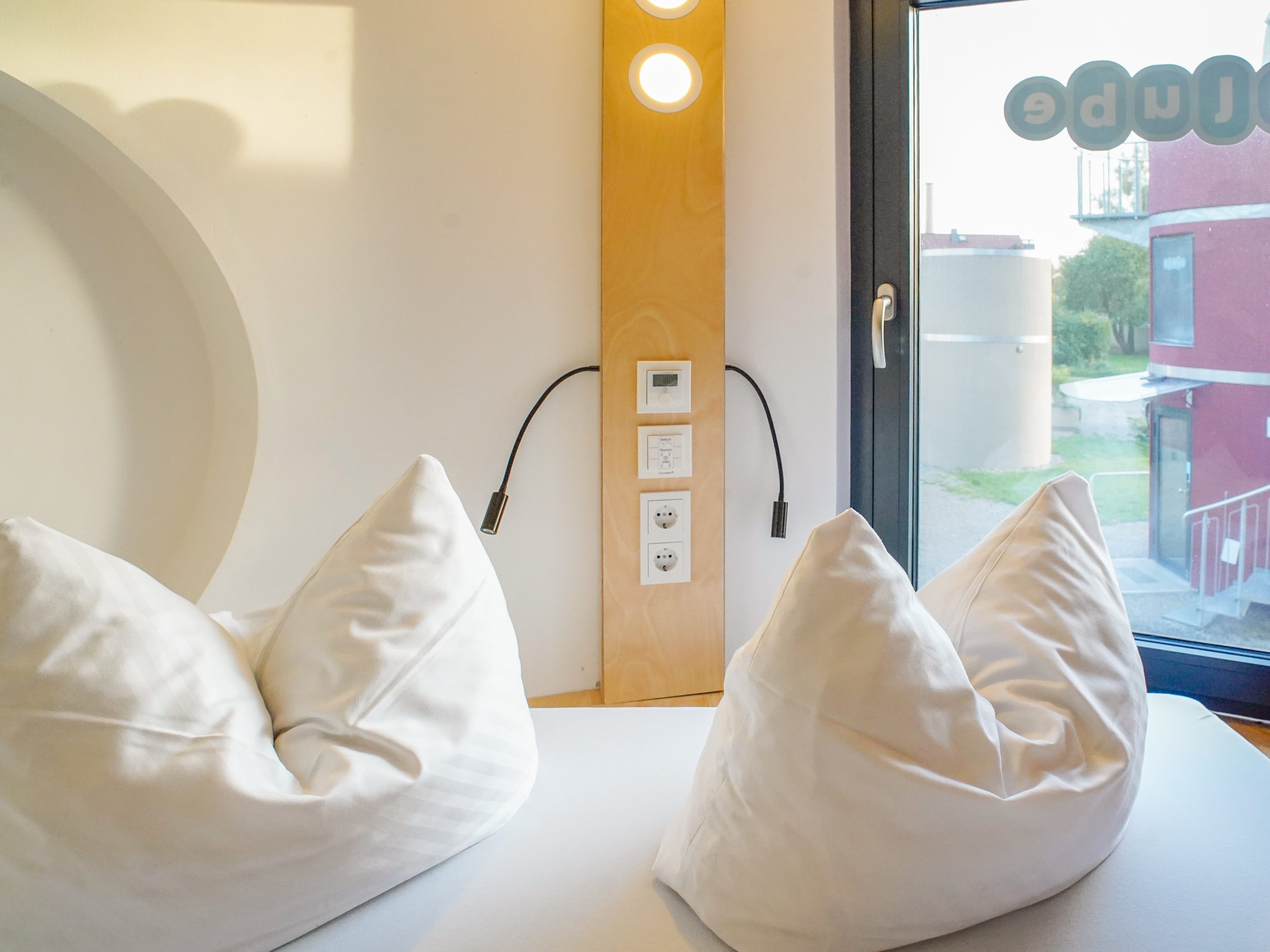 The tiny home bed with two pillows on it and a shelf behind