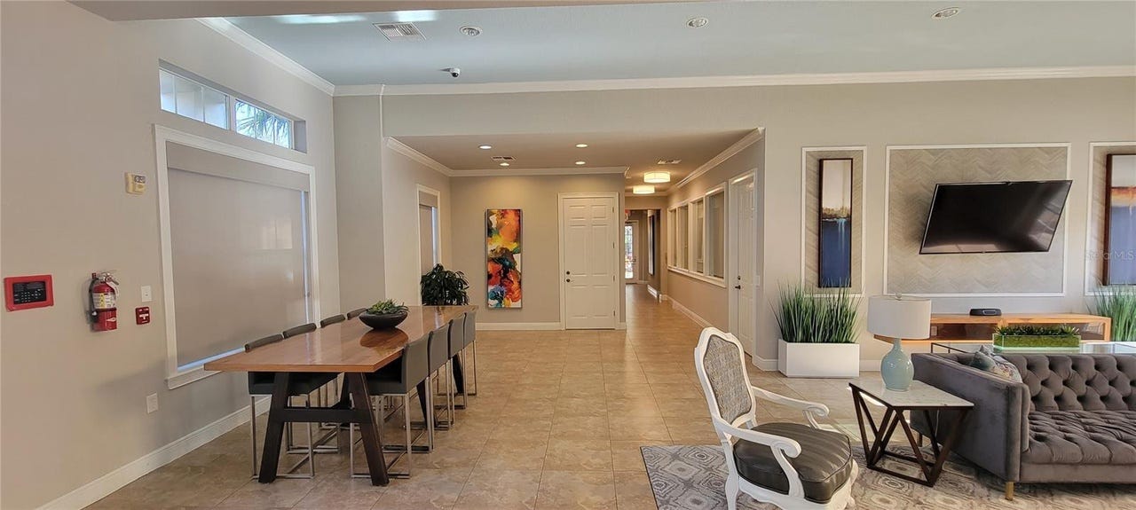 The living room of the home has a dinner table, a couch, and a television.