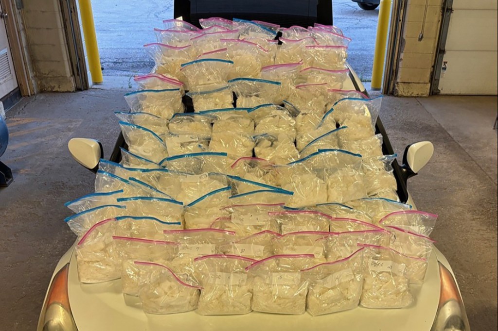 Numerous bags of seized drugs on a car hood.