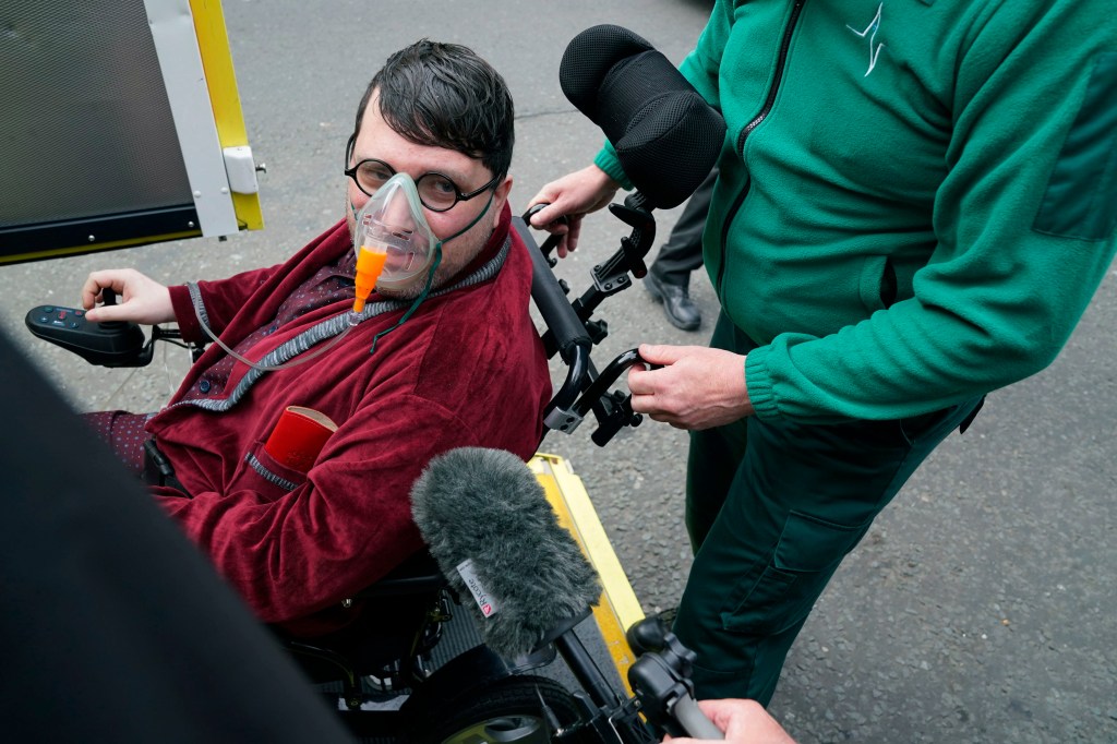 Man in wheelchair wearing an oxygen mask arrives at court.