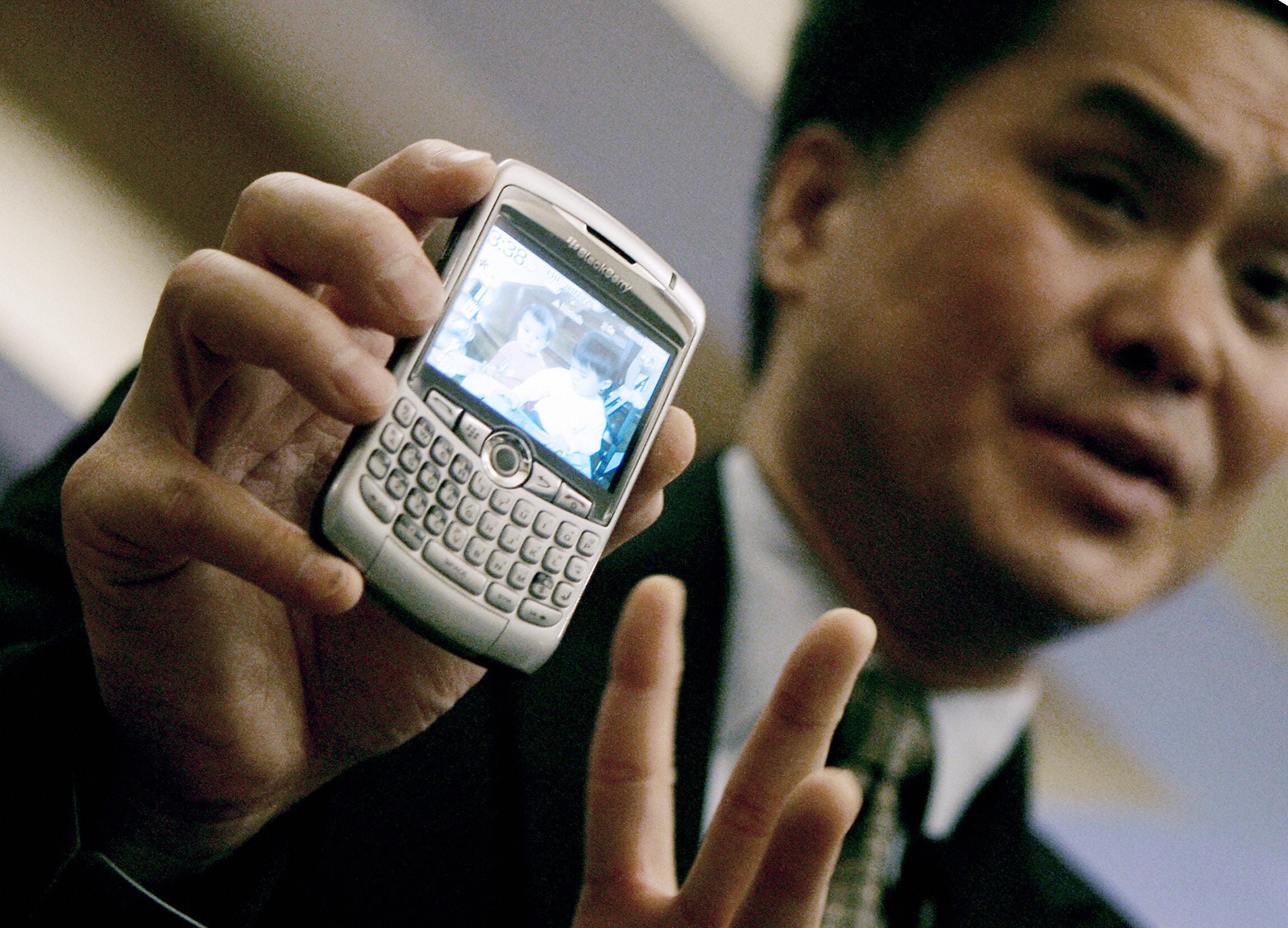 Man holds up a silver Blackberry phone