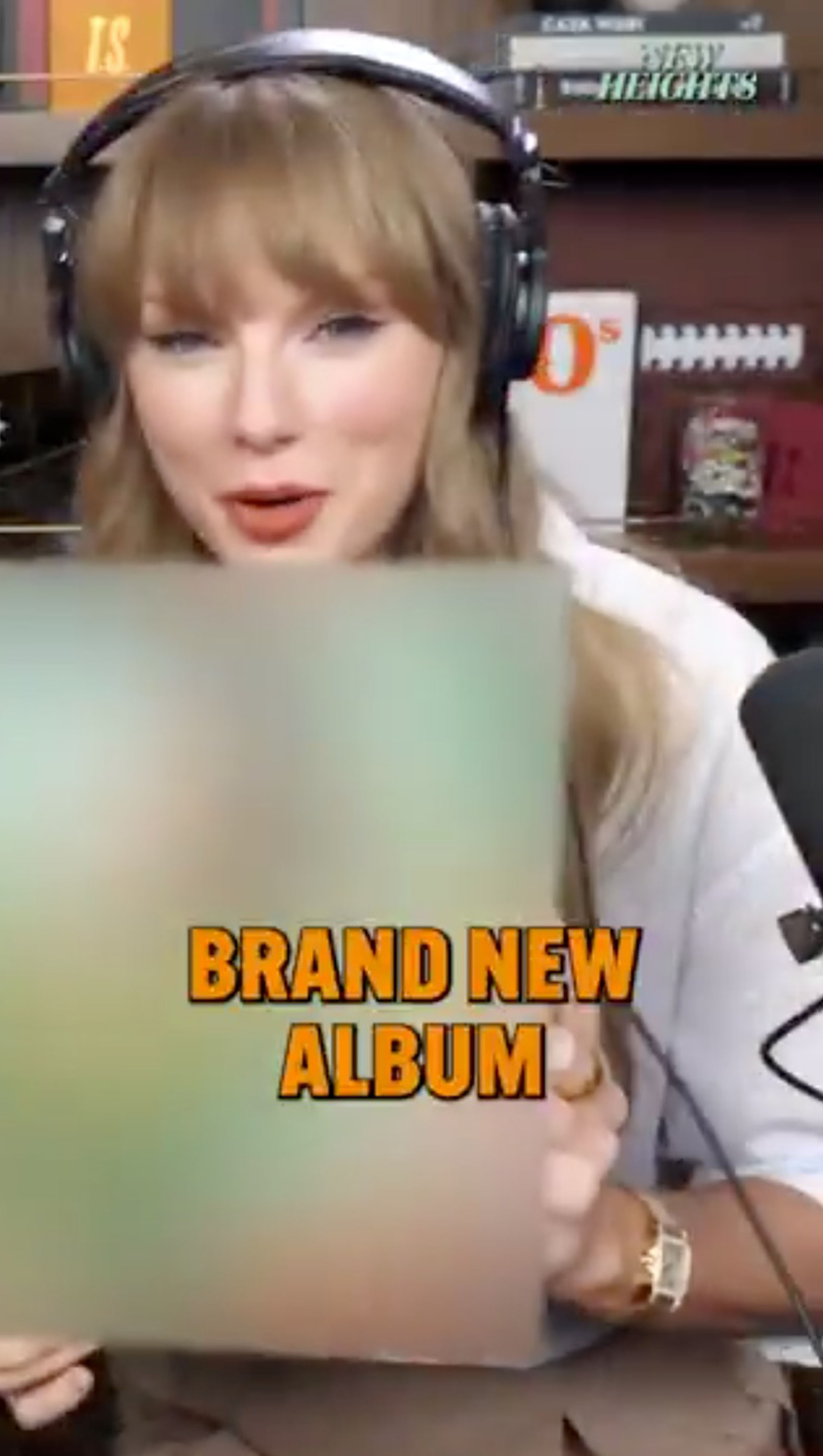 Taylor Swift holding her new album with a blurred cover