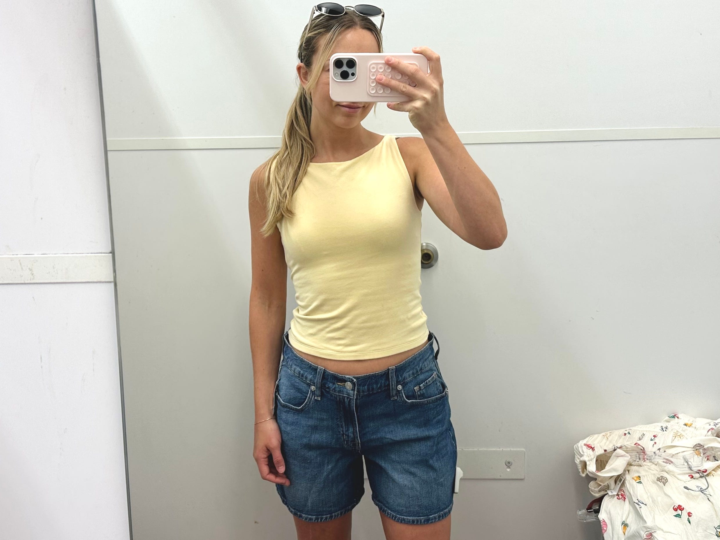 Chloe trying on jean shorts in a Gap fitting room.