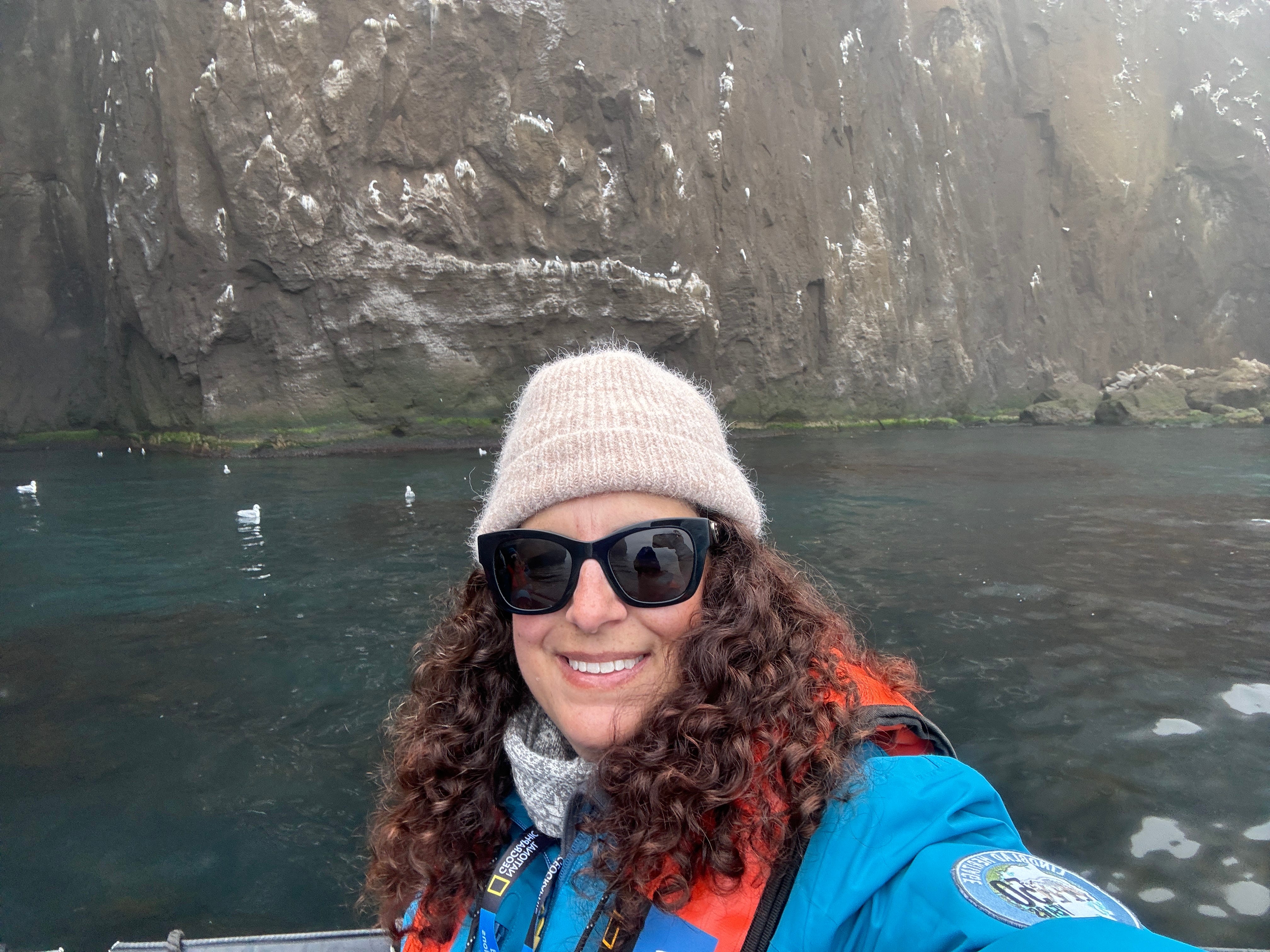 Author Author Jamie Davis Smith in front of body of water with hat, jacket on in Iceland