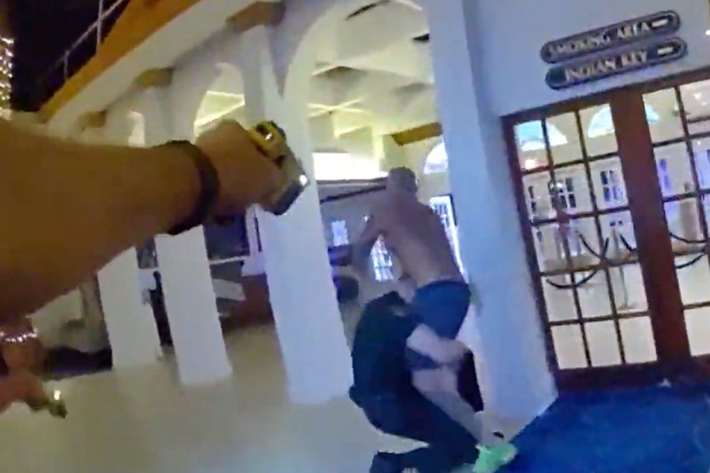 A shirtless man being tackled by a police officer.