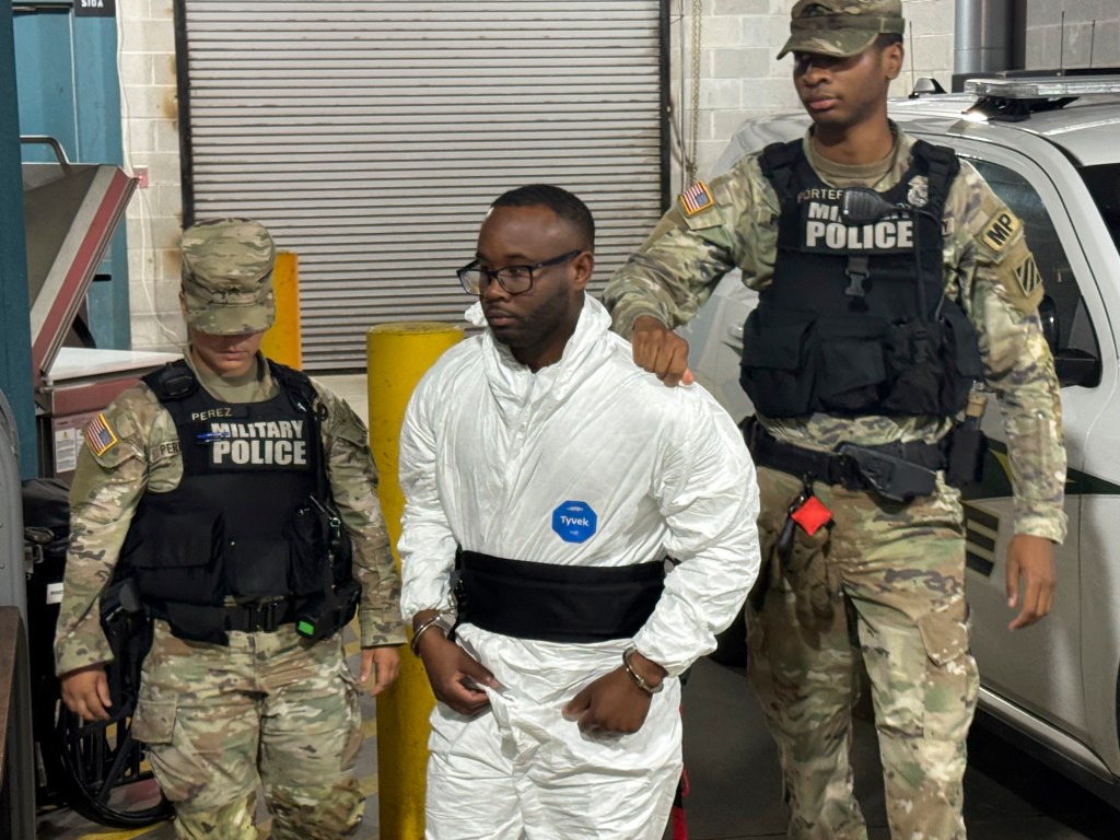 Suspect in Fort Stewart shooting escorted by military police.