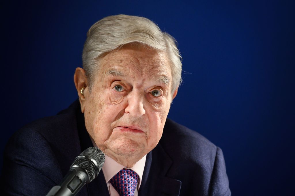 George Soros speaking at a microphone.