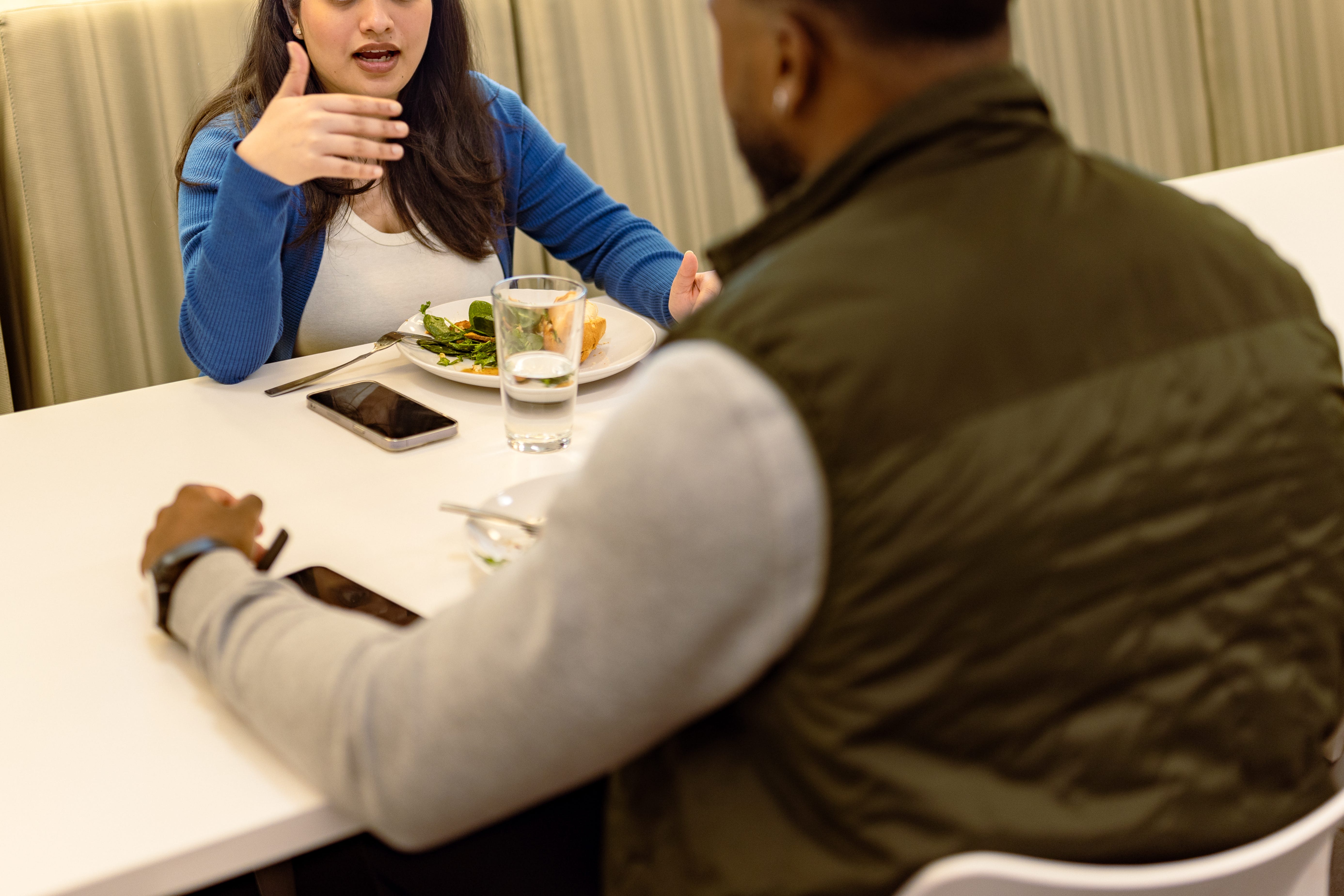Two colleagues having a conversation over lunch in a modern office cafeteria during the day
