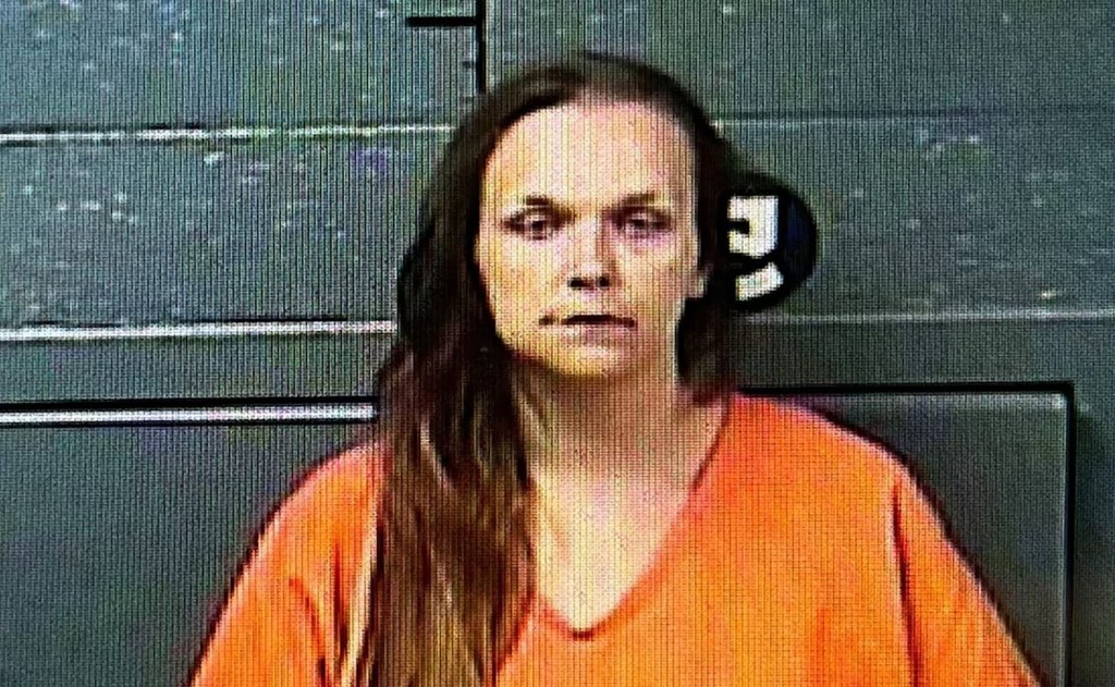 Mugshot of a woman in an orange jumpsuit.