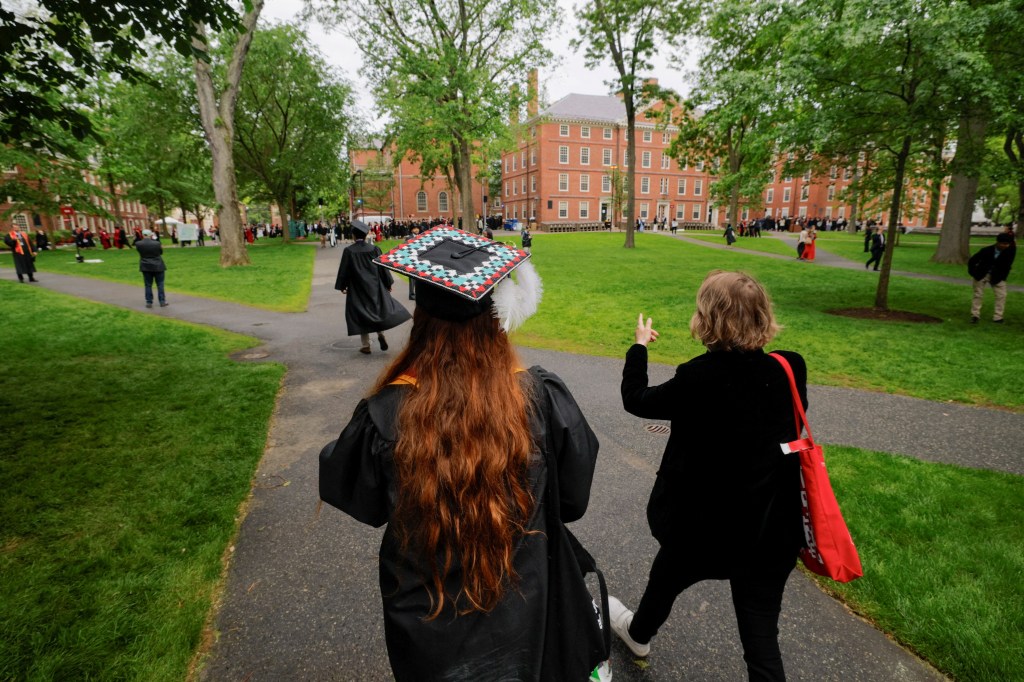 Graduate walks across Harvard Yard during commencement.