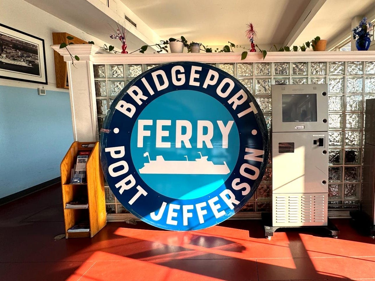 An indoor waiting area with a sign that reads "Bridgeport Port Jefferson Ferry."