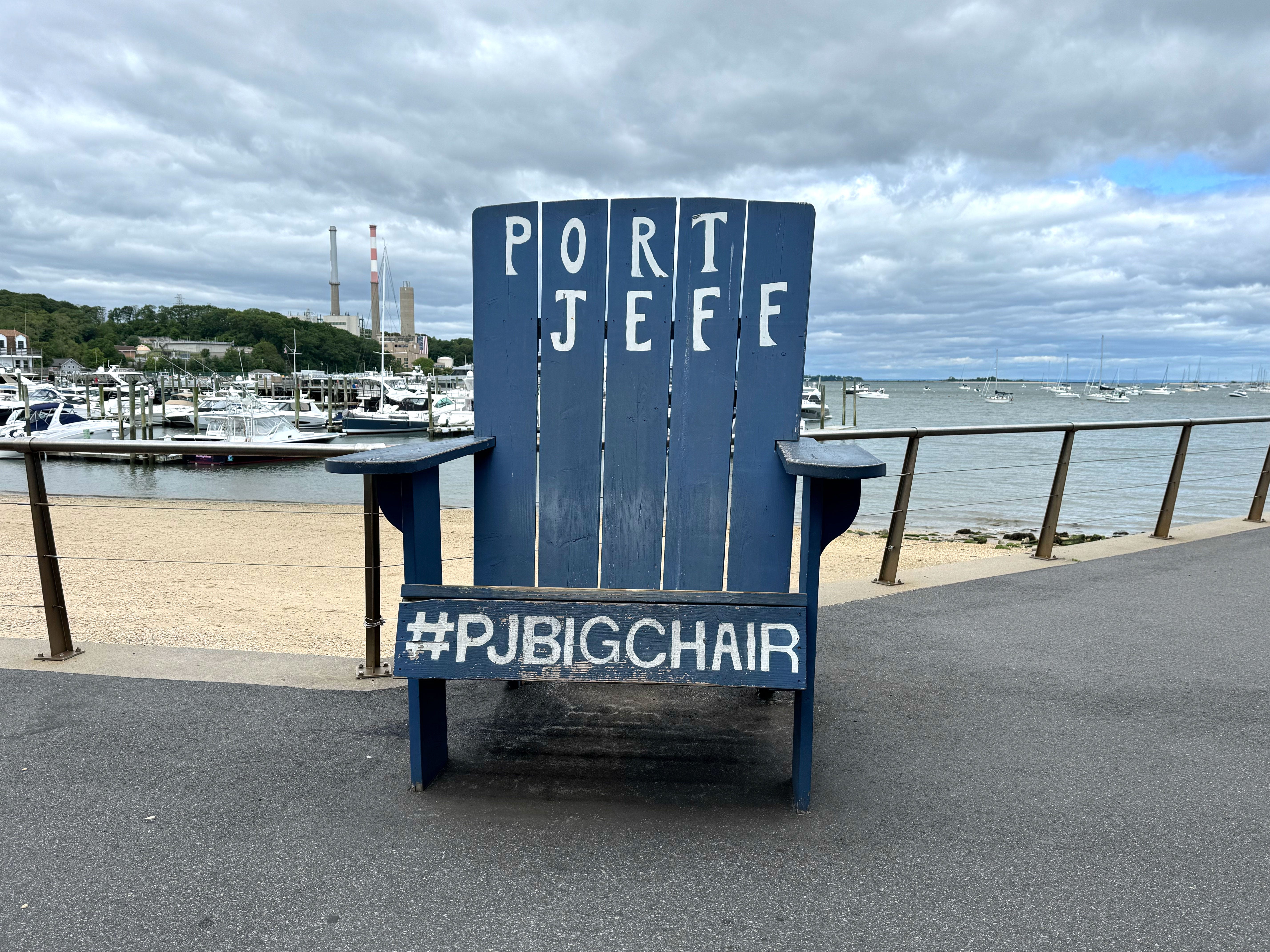 An oversize blue Adirondack chair that says "Port Jeff #PJBigChair."