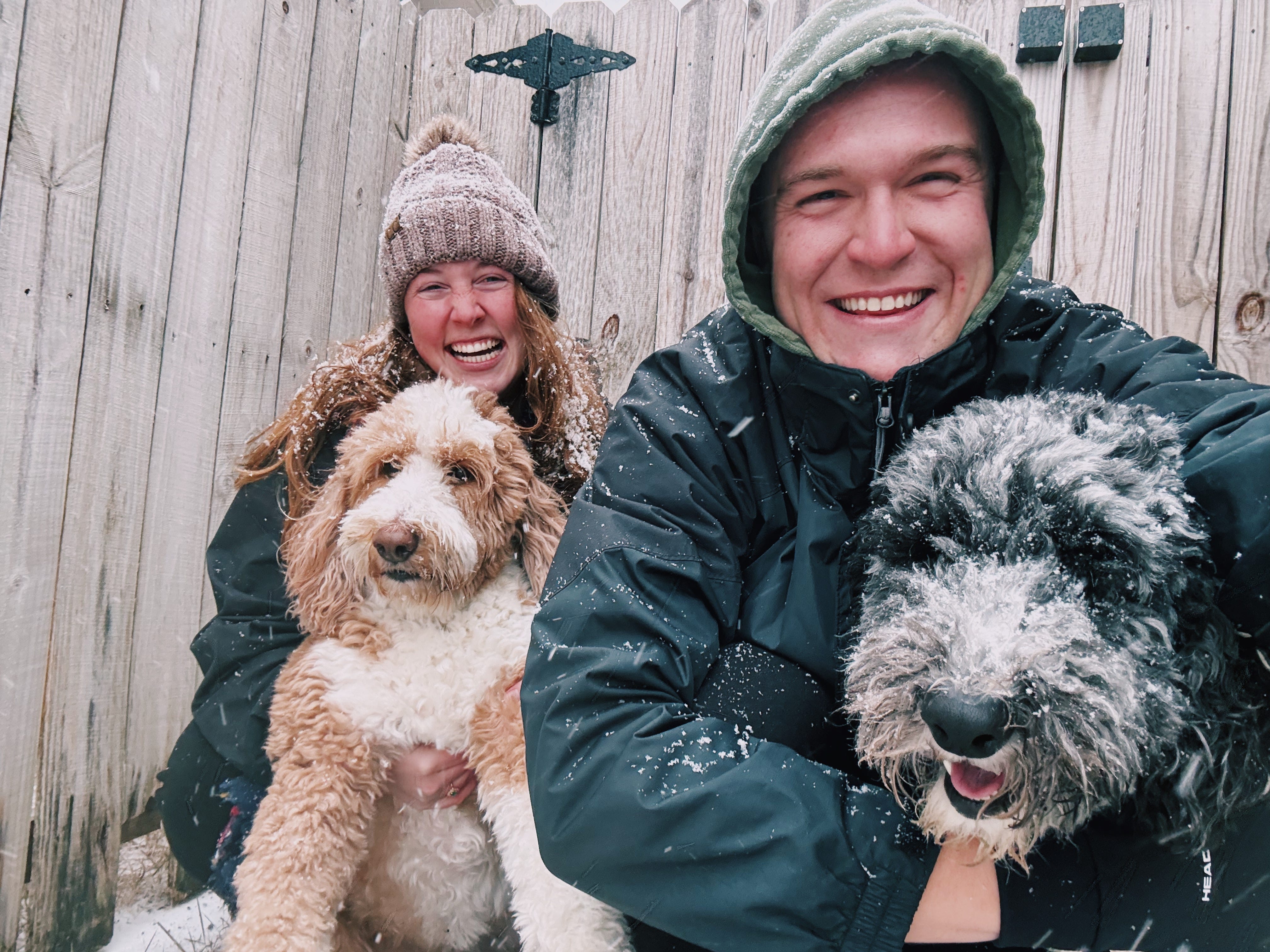 Author Allie Hubers and husband smiling in snow with two dogs