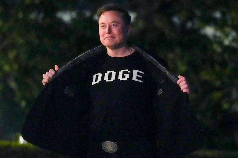 Elon Musk shows off a shirt that says "DOGE" as he walks on the South Lawn of the White House on March 9, 2025.