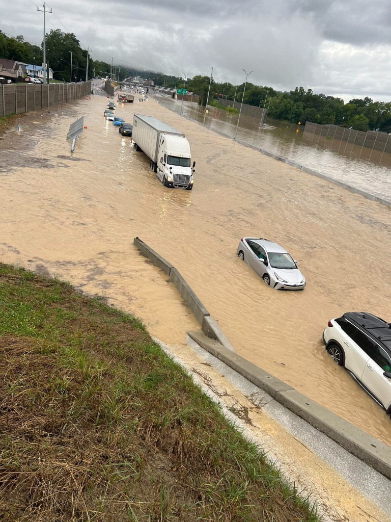Flooded highway with several submerged vehicles.