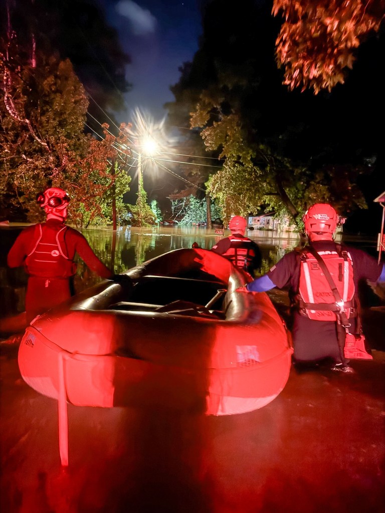 Swiftwater rescue team using an inflatable boat during a nighttime flood rescue.