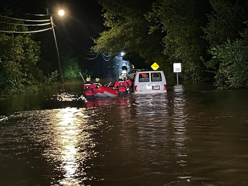 Firefighters rescuing people from a flooded van.