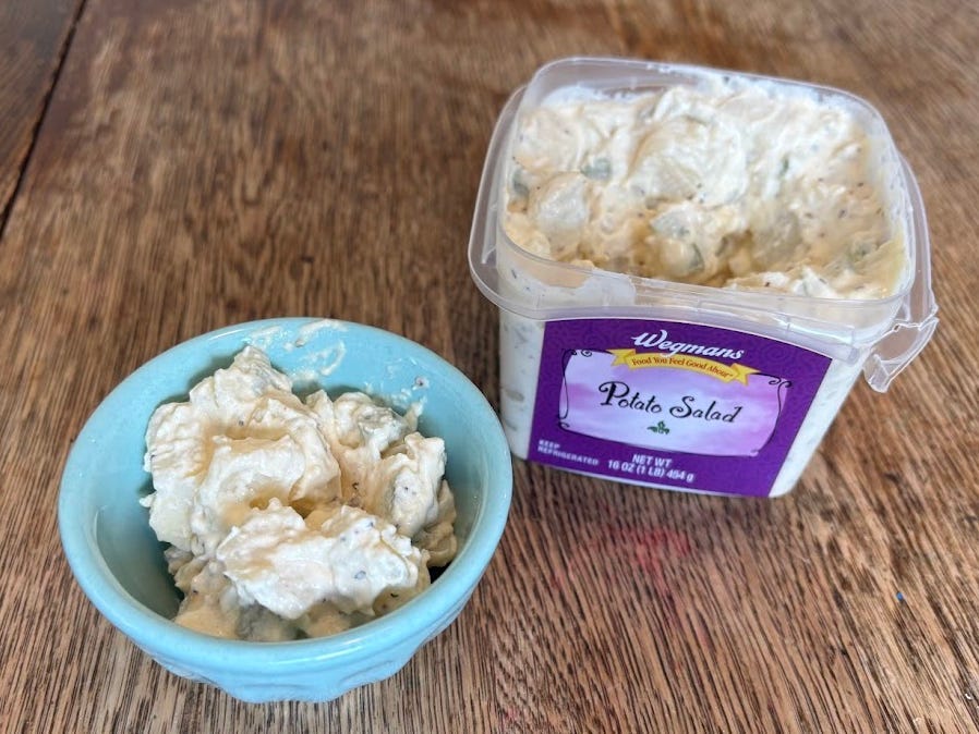 A small turquoise bowl of Wegmans potato salad next to the package.