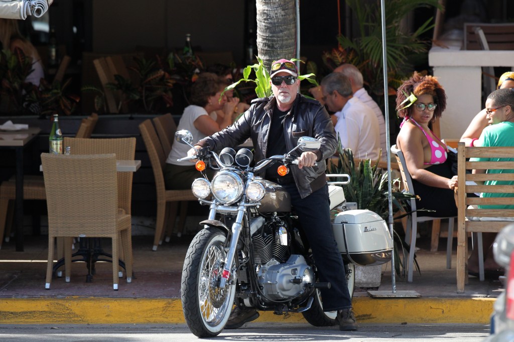 Billy Joel sitting on a motorcycle.