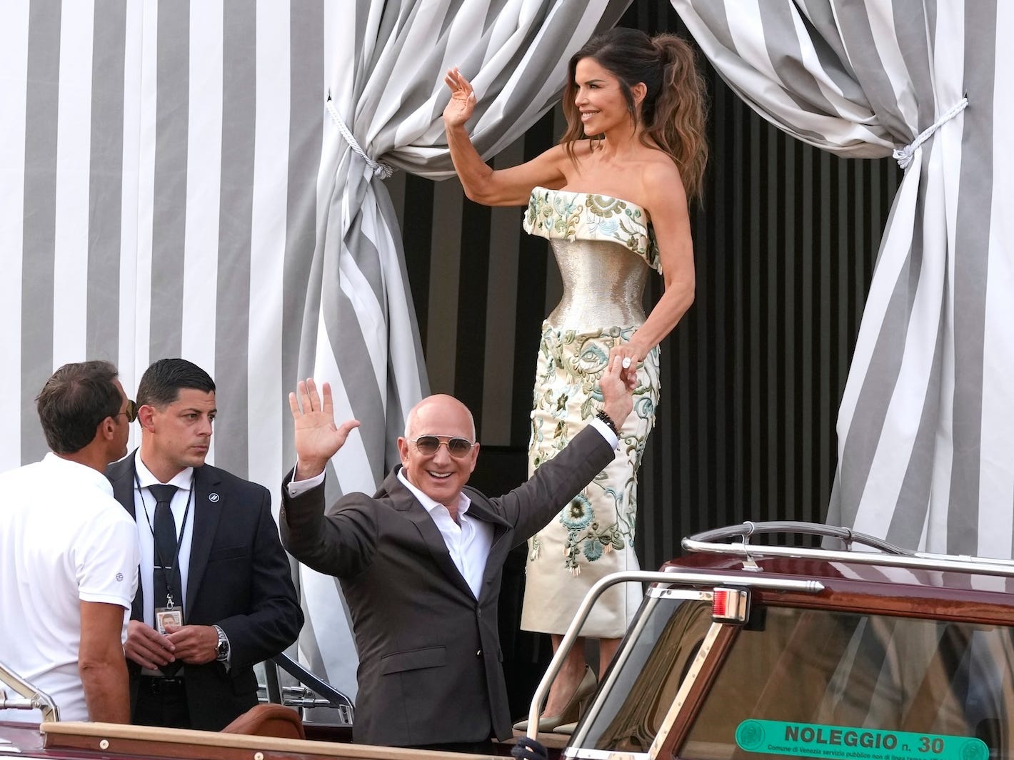 Jeff Bezos and Lauren Sánchez wave at people as they board a boat in Venice.